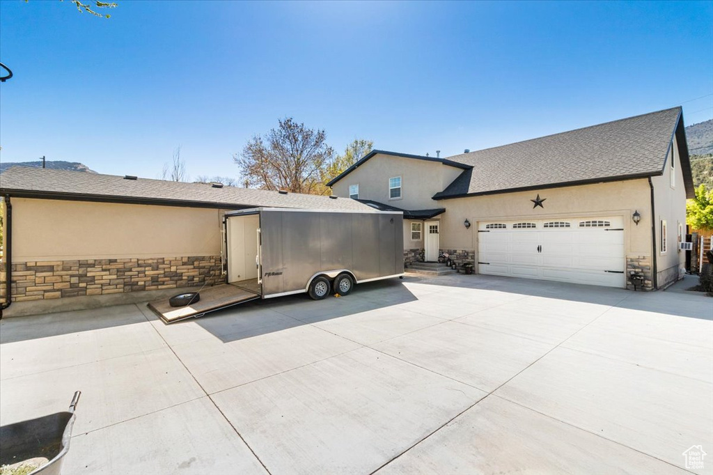 Back of house featuring stone siding, an attached garage, and stucco siding