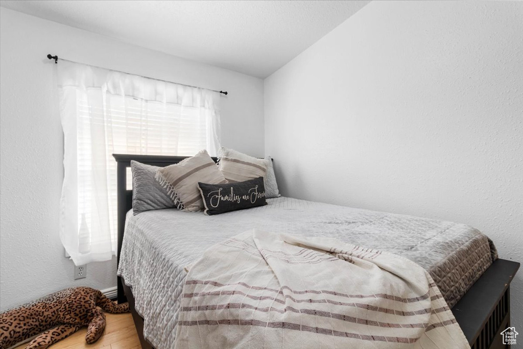 Bedroom with wood finished floors and lofted ceiling