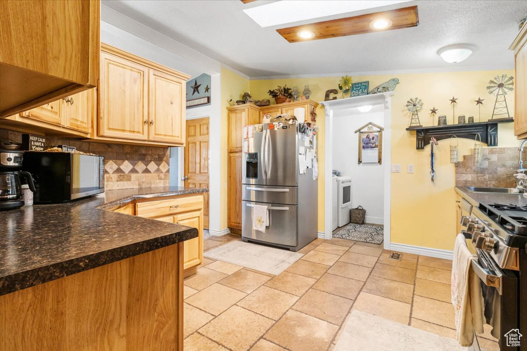 Kitchen featuring appliances with stainless steel finishes, a sink, washer / clothes dryer, backsplash, and ornamental molding