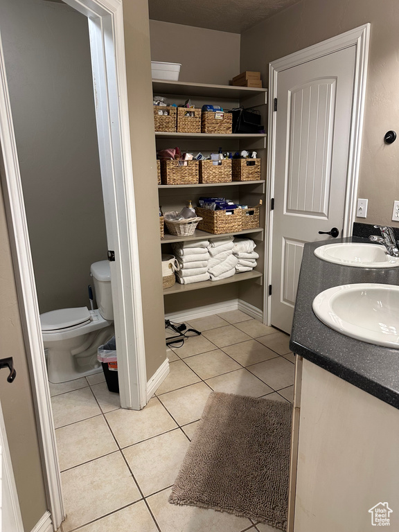 Bathroom with tile patterned floors, toilet, and double vanity