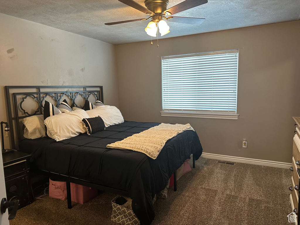 Carpeted bedroom featuring a textured ceiling, ceiling fan, and baseboards