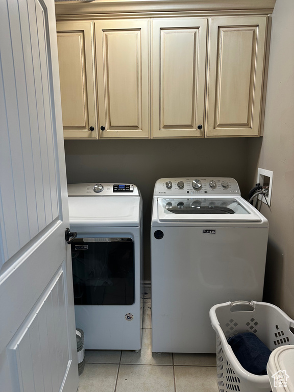 Laundry area featuring independent washer and dryer, cabinet space, and light tile patterned flooring