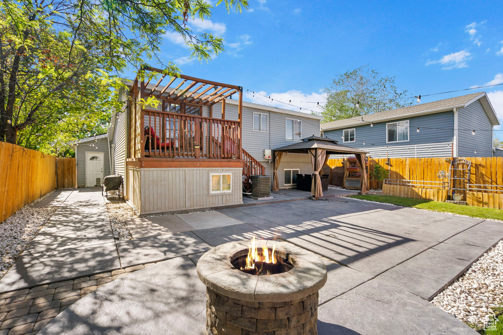 Rear view of house featuring a gazebo, a patio area, an outdoor fire pit, and a fenced backyard