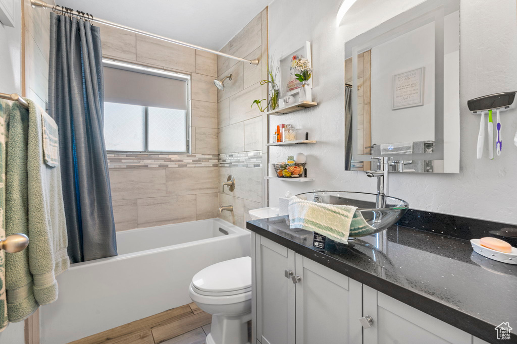 Bathroom featuring shower / tub combo with curtain, toilet, vanity, and wood finished floors