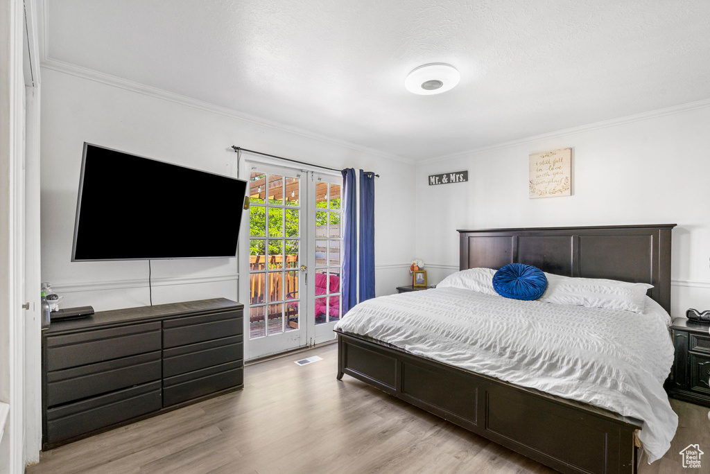 Bedroom featuring access to outside, crown molding, light wood-type flooring, and french doors