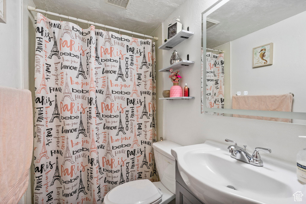 Full bath featuring toilet, a textured ceiling, vanity, and a shower with curtain