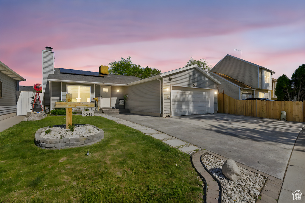 View of front of house with concrete driveway, roof mounted solar panels, a garage, and a chimney