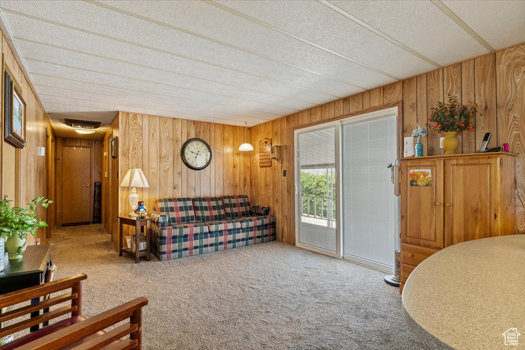 Carpeted living area featuring wooden walls and a textured ceiling