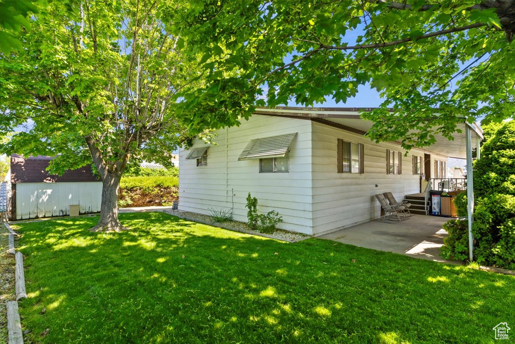 Back of house featuring a lawn, a patio, and an outbuilding