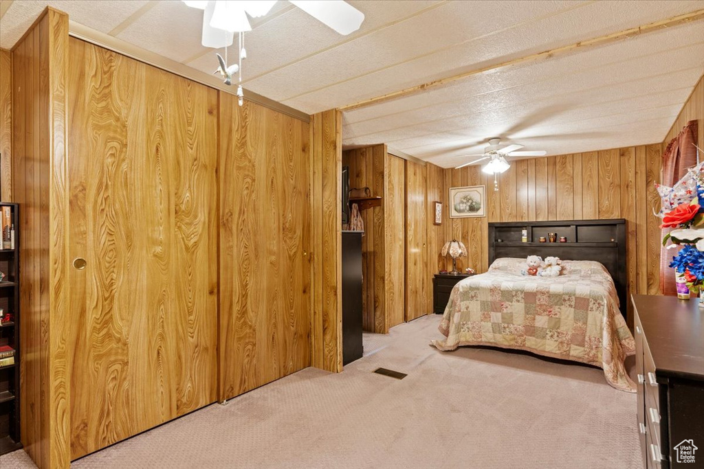 Carpeted bedroom with wooden walls and ceiling fan