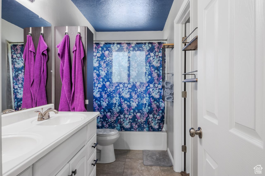 Bathroom with double vanity, toilet, and shower / bath combination with curtain