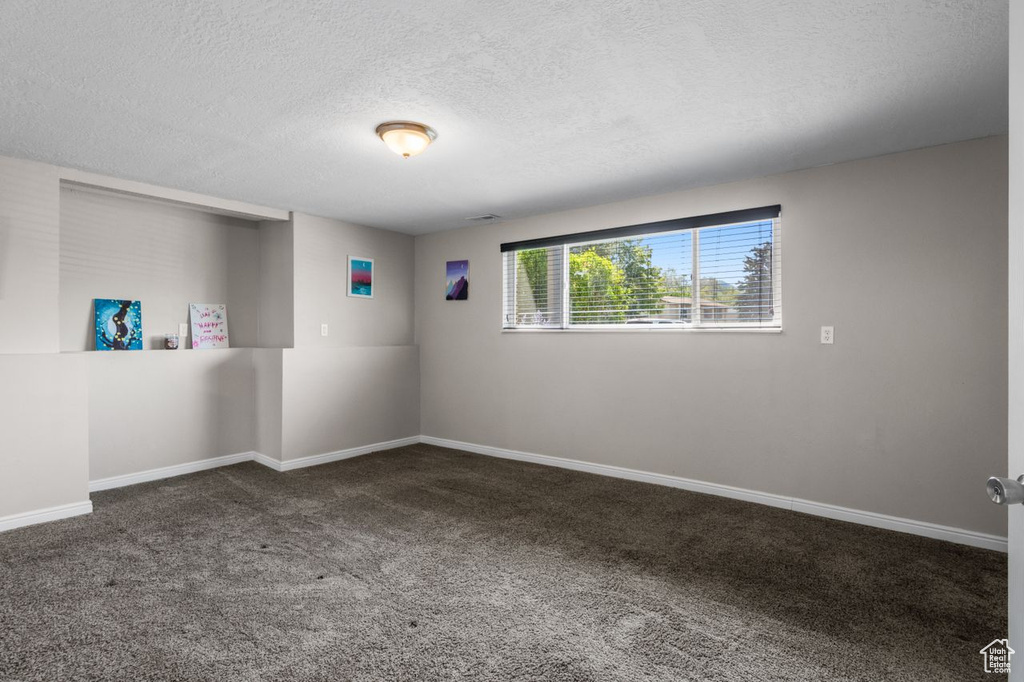 Carpeted spare room with a textured ceiling and baseboards