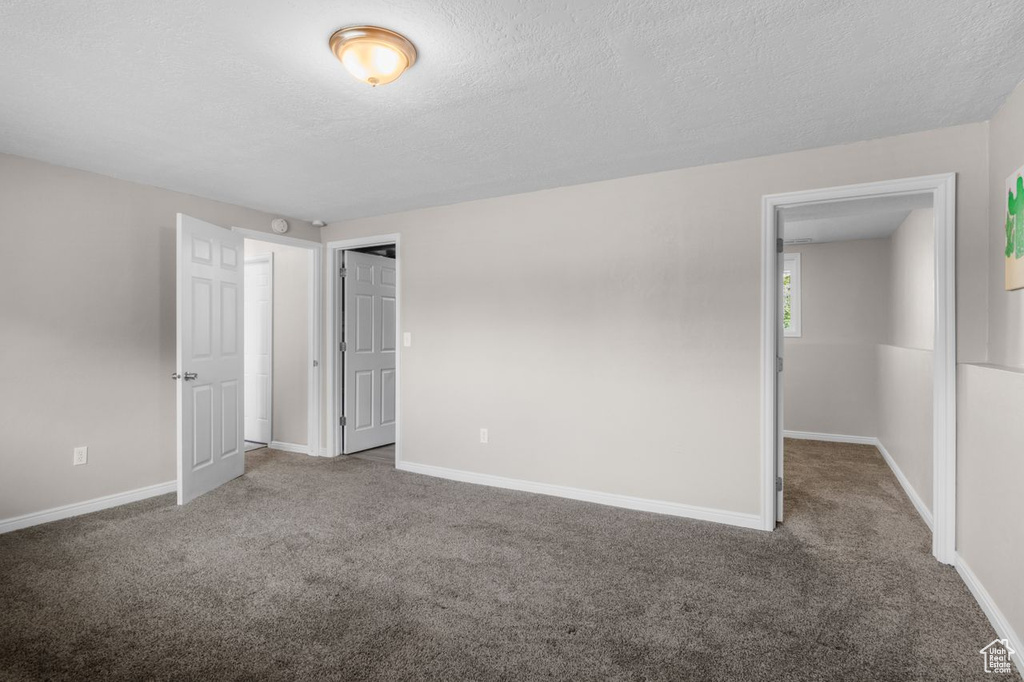 Unfurnished bedroom featuring carpet, a textured ceiling, and baseboards