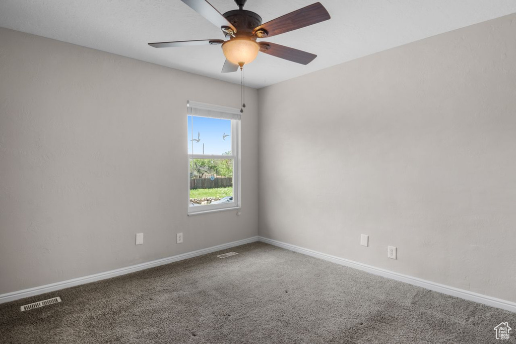 Unfurnished room featuring carpet flooring, baseboards, and ceiling fan