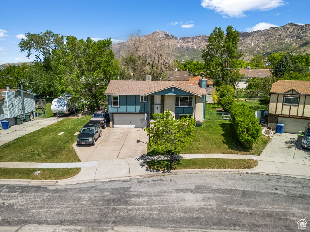 View of front of house with driveway, a mountain view, a garage, and a chimney