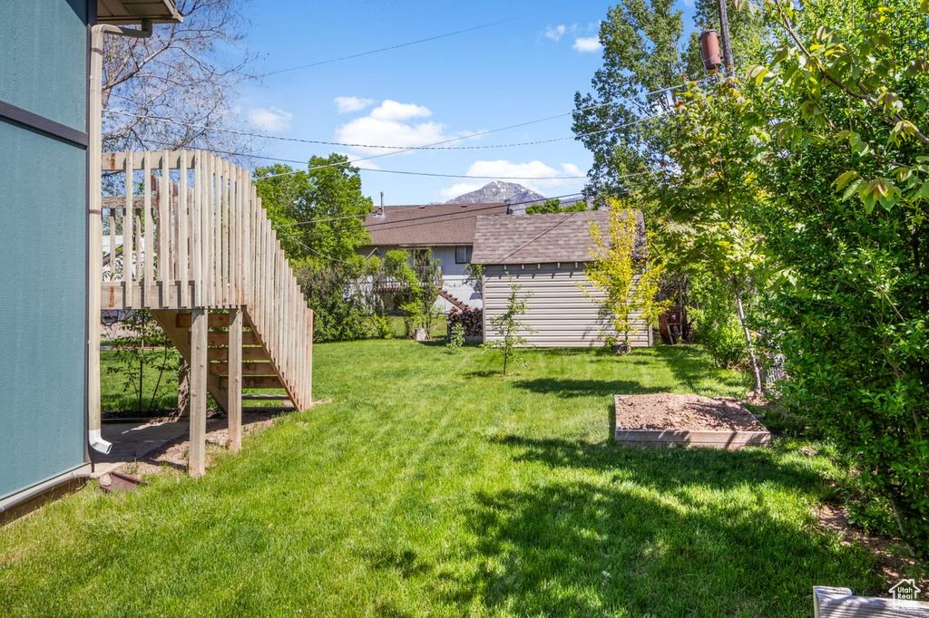 View of grassy yard featuring stairway and an outbuilding