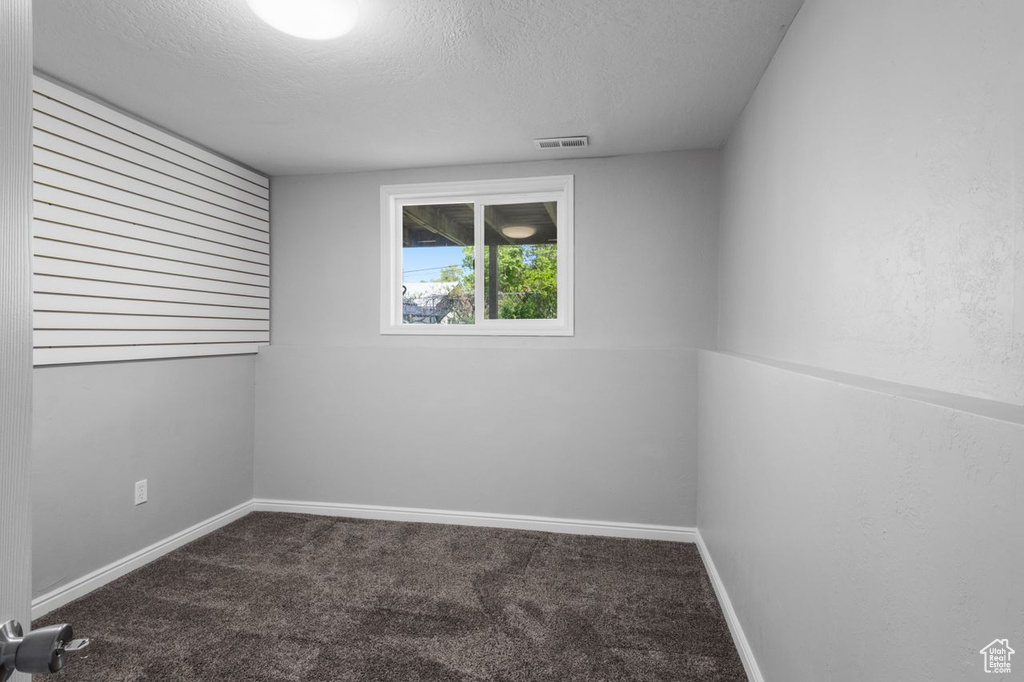 Empty room featuring carpet, a textured ceiling, and baseboards