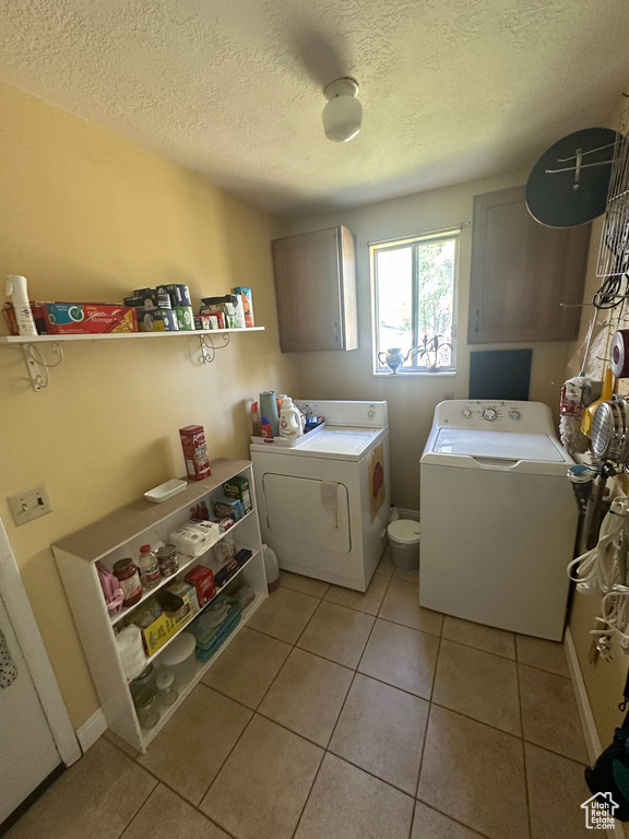 Laundry room with washing machine and dryer, a textured ceiling, light tile patterned floors, and cabinet space