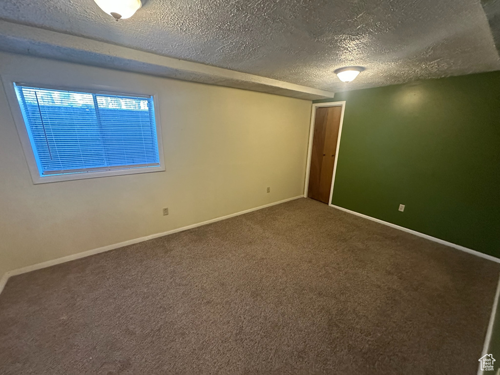 Carpeted spare room with a textured ceiling and baseboards