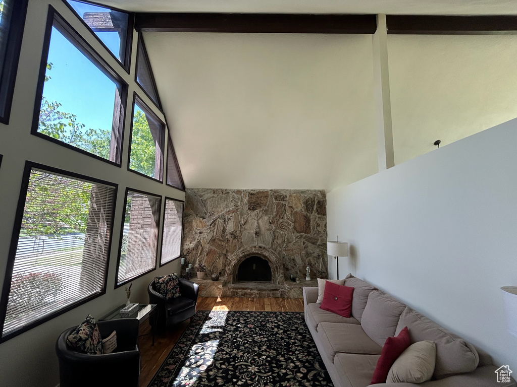 Living room featuring wood finished floors, high vaulted ceiling, healthy amount of natural light, and a fireplace