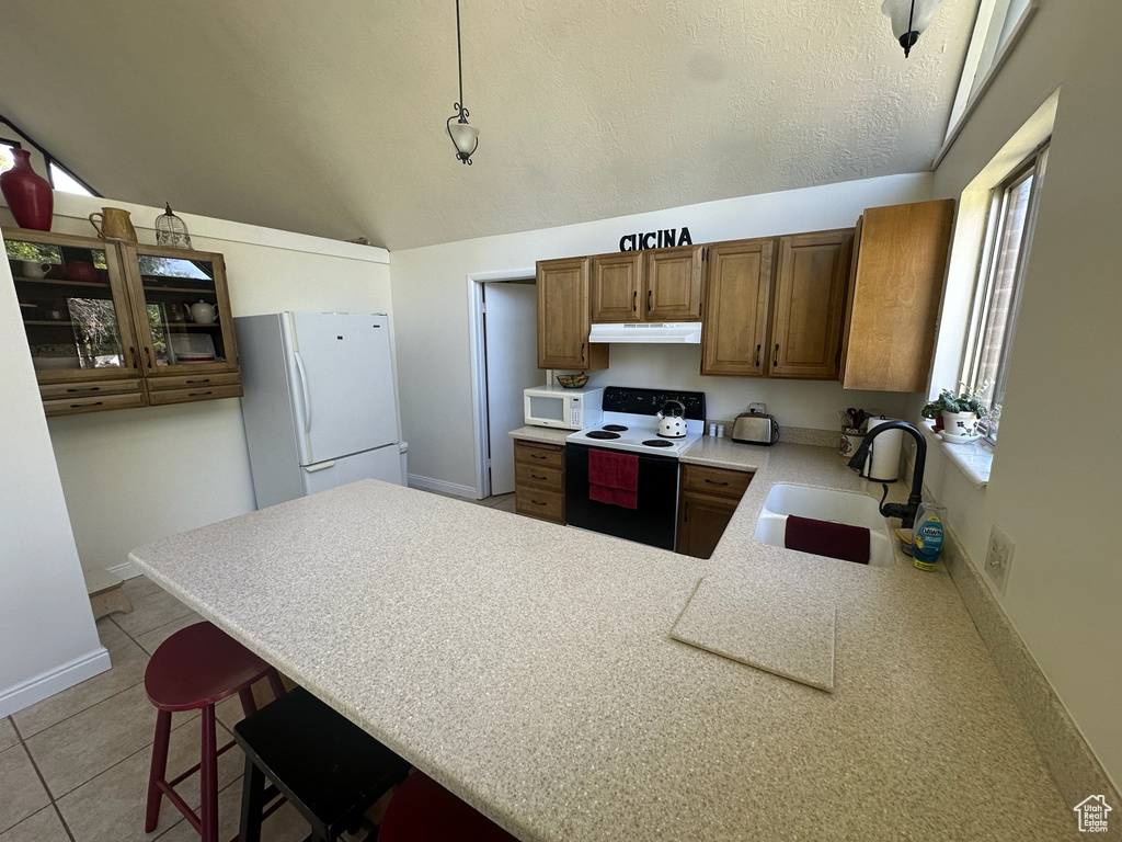 Kitchen featuring white appliances, a sink, a peninsula, light countertops, and brown cabinetry