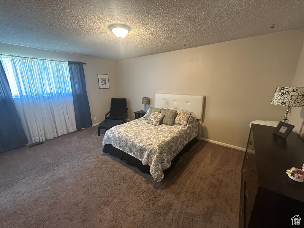 Carpeted bedroom featuring a textured ceiling and baseboards