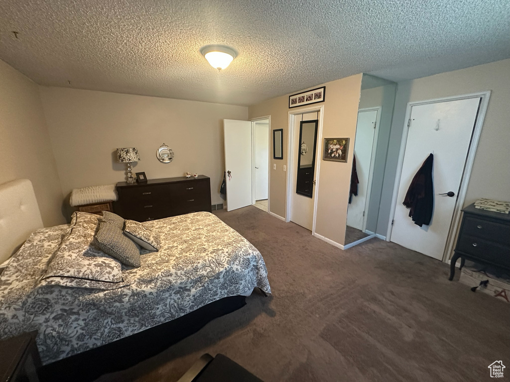 Bedroom featuring dark carpet and a textured ceiling