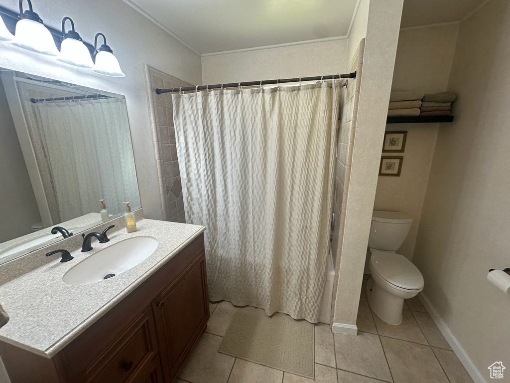 Full bathroom featuring toilet, tile patterned floors, vanity, crown molding, and shower / bathtub combination with curtain
