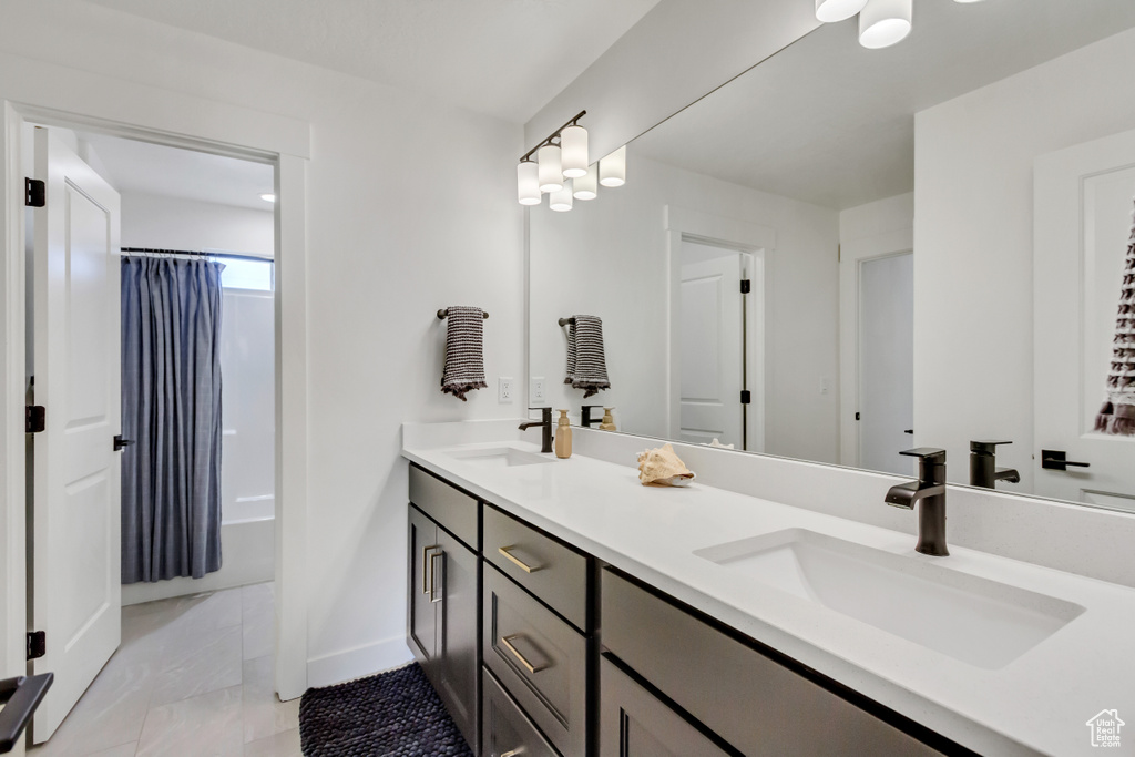 Bathroom featuring double vanity, baseboards, and shower / bathtub combination with curtain