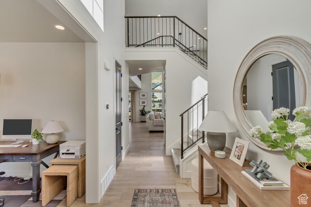 Foyer entrance featuring light wood-type flooring, a towering ceiling, and stairway