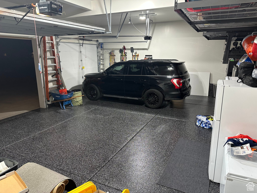 Garage with a garage door opener and freestanding refrigerator
