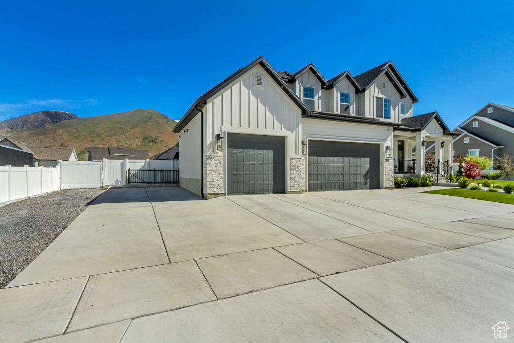 View of front of home featuring board and batten siding, concrete driveway, fence, a garage, and stone siding