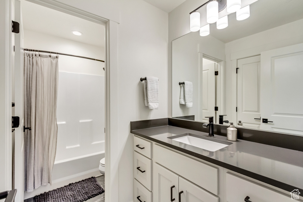 Bathroom featuring toilet, vanity, and shower / bathtub combination with curtain