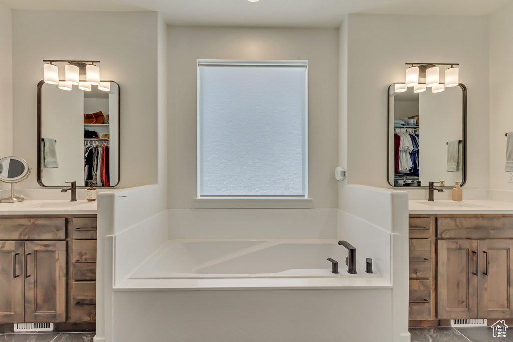 Full bath featuring two vanities, a garden tub, and a spacious closet