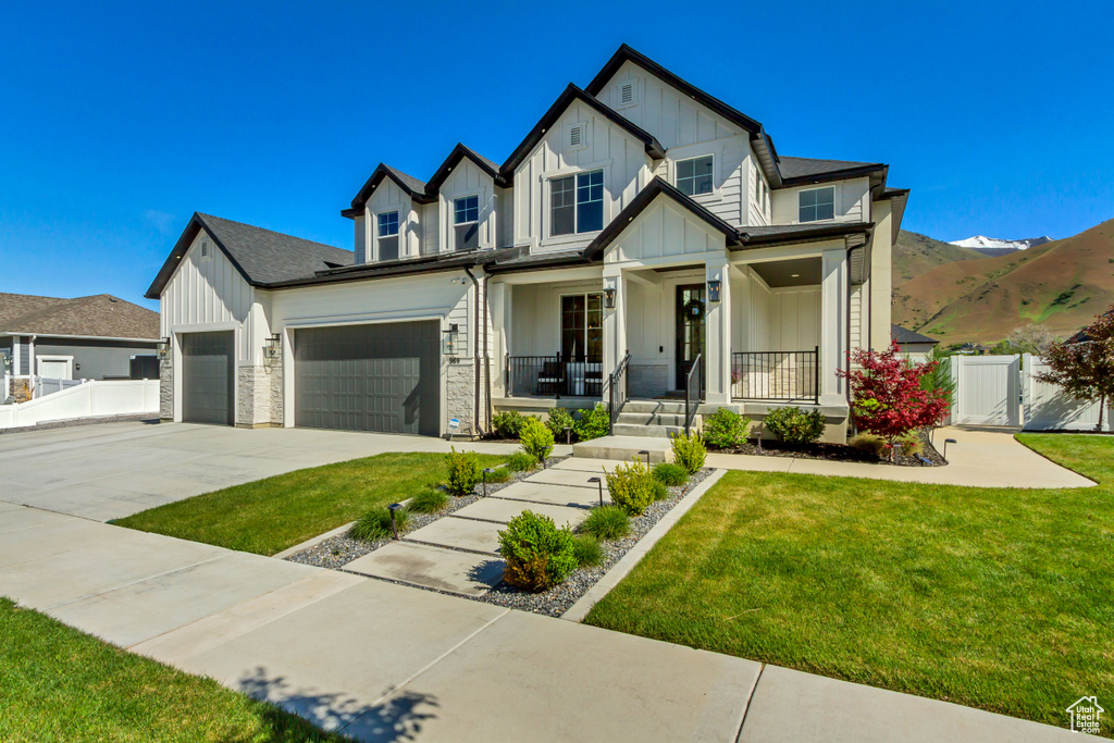 View of front of home featuring board and batten siding, covered porch, concrete driveway, an attached garage, and a gate