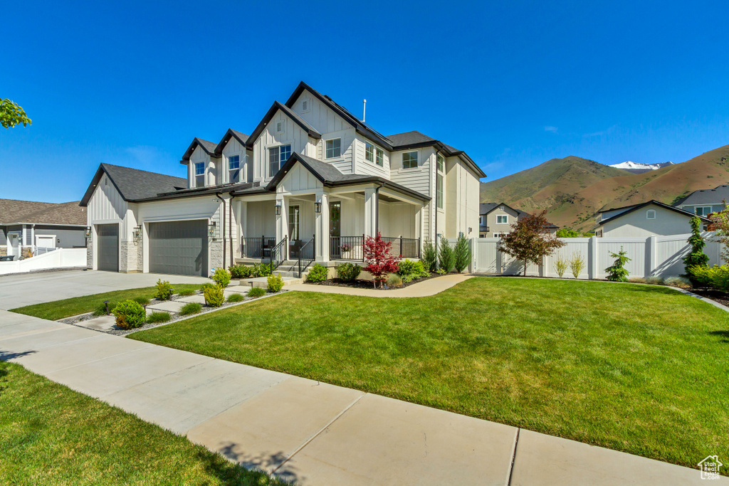 View of front of house with board and batten siding, covered porch, a garage, driveway, and a mountain view