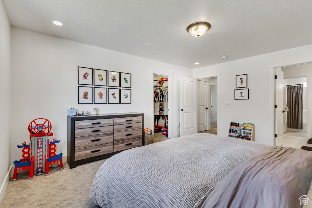Bedroom featuring carpet floors, a walk in closet, baseboards, a closet, and ensuite bathroom