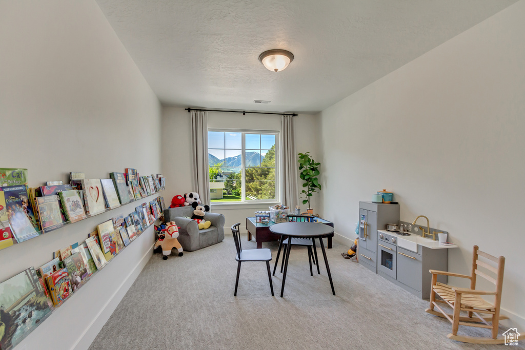 Playroom with light carpet, a textured ceiling, and baseboards