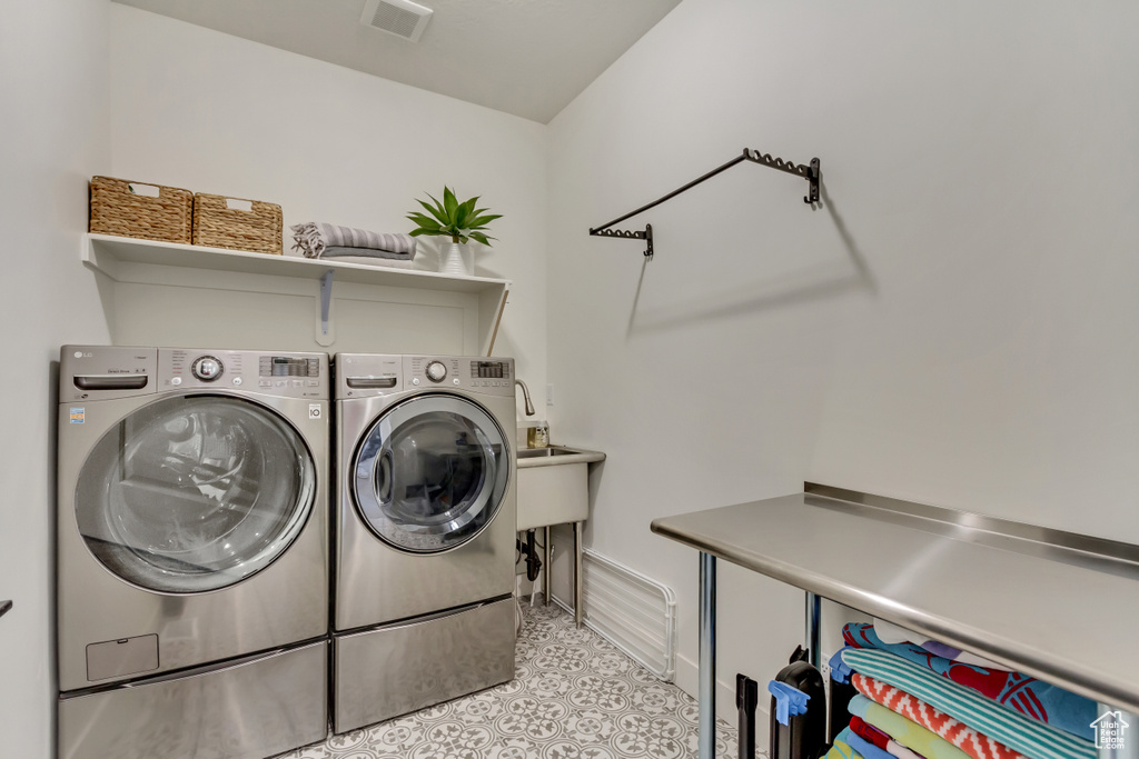 Clothes washing area featuring washing machine and clothes dryer and baseboards