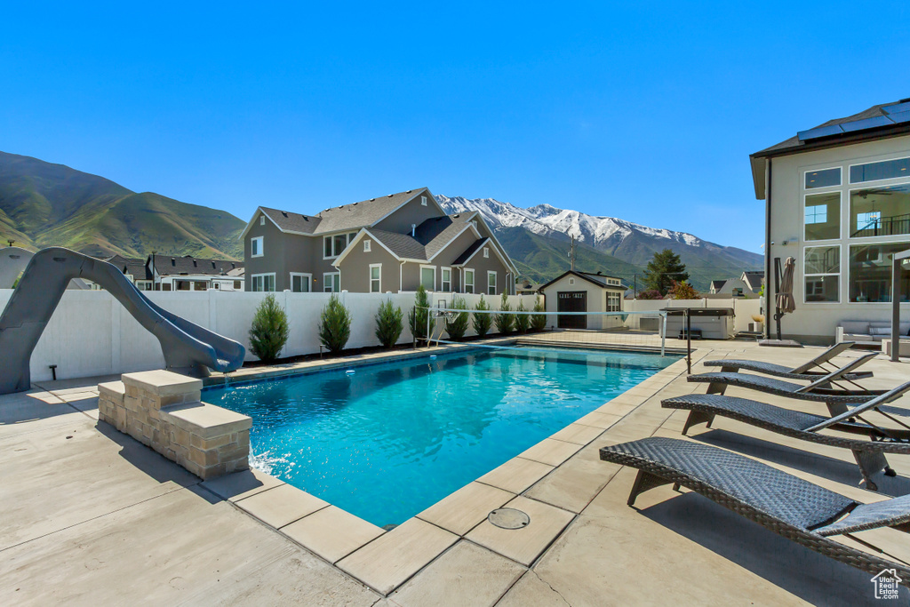 View of pool featuring a water slide, a mountain view, a shed, and an outbuilding
