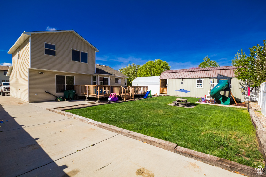 Rear view of house with a wooden deck, a patio area, and an outbuilding