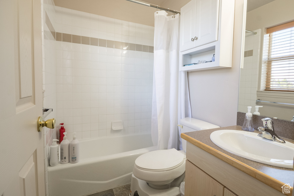 Full bathroom with vanity, toilet, and shower / bath combo with shower curtain