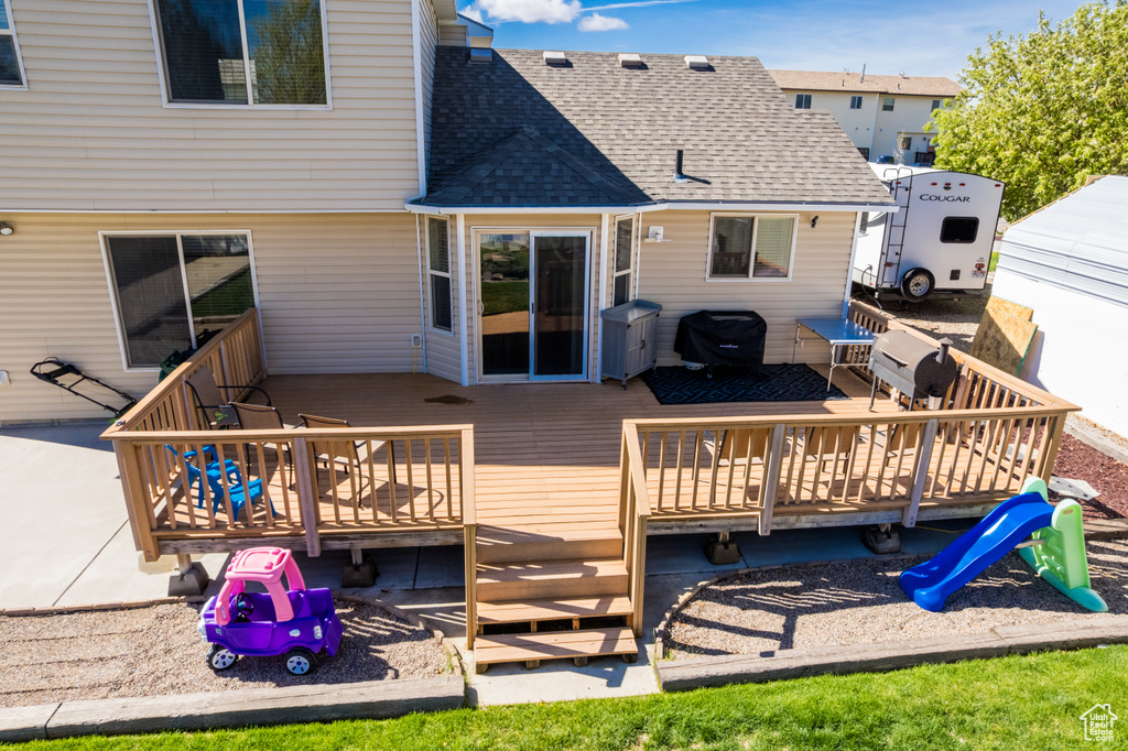 Back of house featuring a shingled roof, a deck, and outdoor dining area