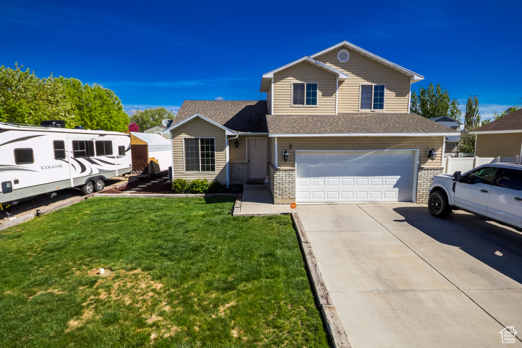 Traditional-style house featuring an attached garage, driveway, a front lawn, brick siding, and a shingled roof