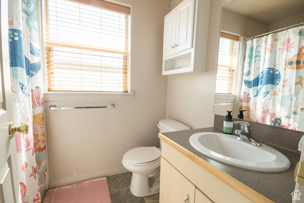 Bathroom with vanity, tile patterned floors, toilet, baseboards, and a shower with curtain