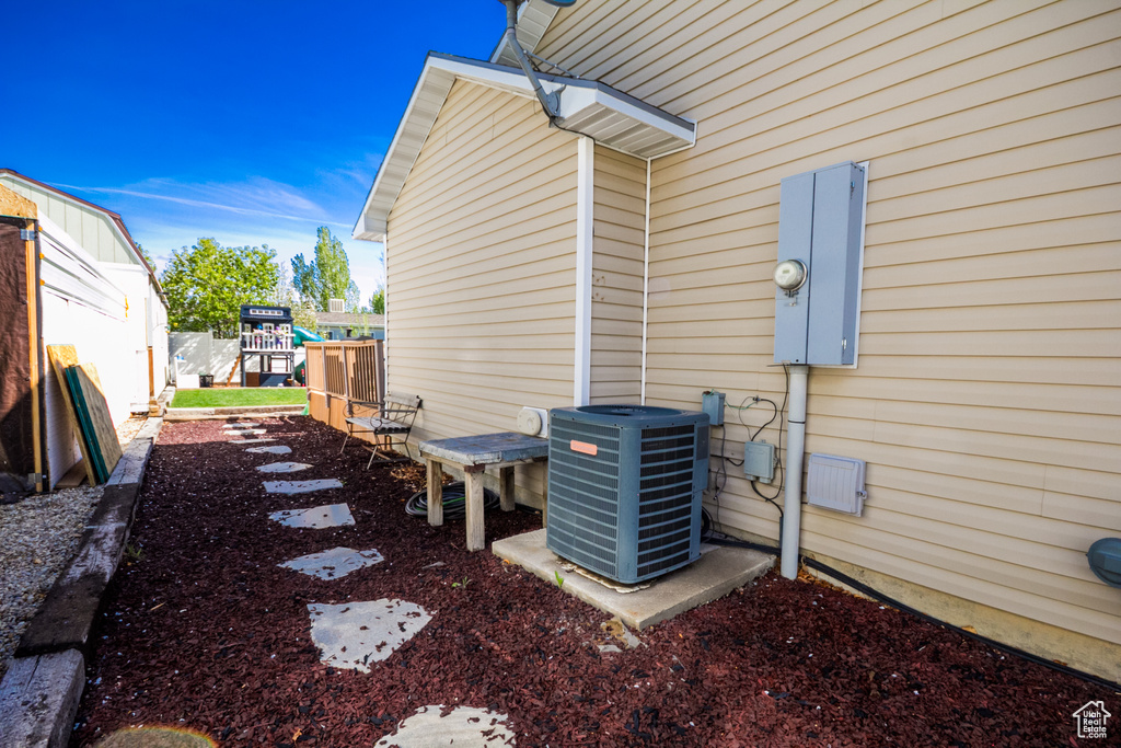 View of side of home with cooling unit and fence