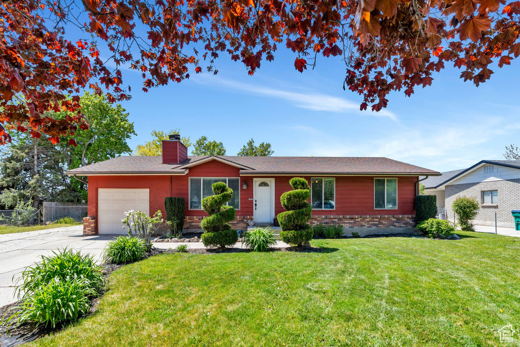 Ranch-style house featuring an attached garage, a chimney, concrete driveway, and brick siding