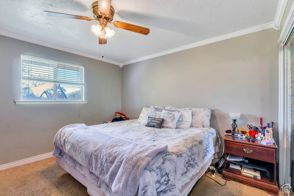 Carpeted bedroom featuring crown molding, baseboards, and a ceiling fan