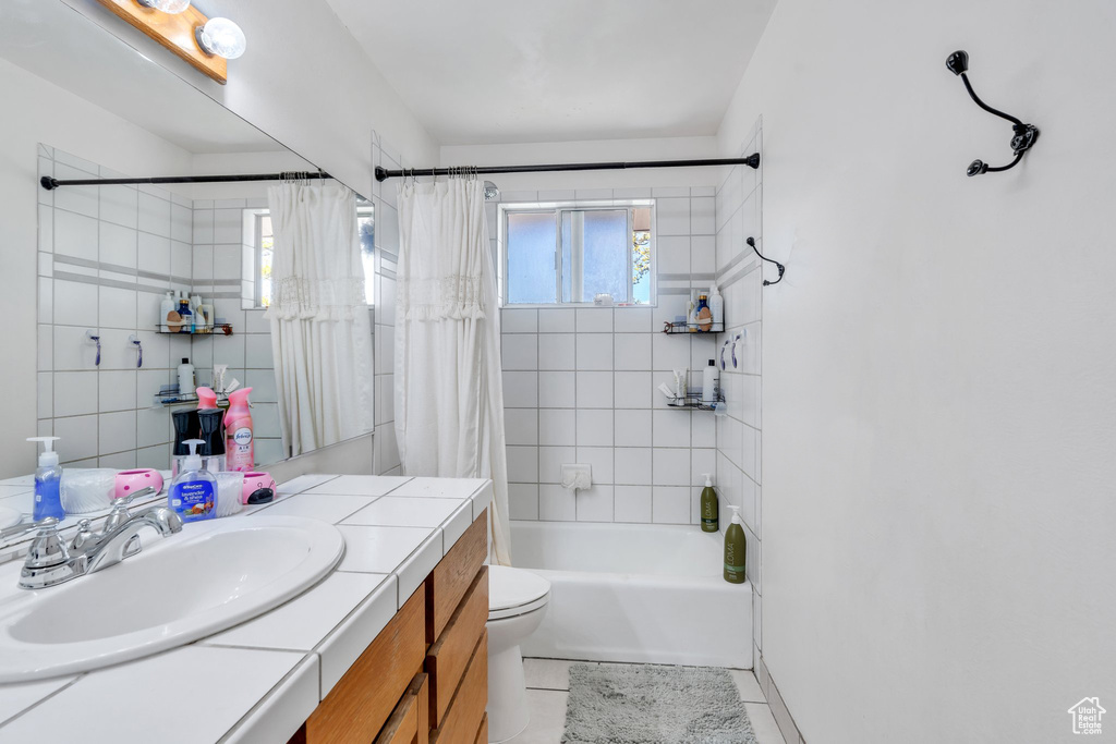 Full bathroom featuring tile patterned flooring, shower / bathtub combination with curtain, vanity, and toilet