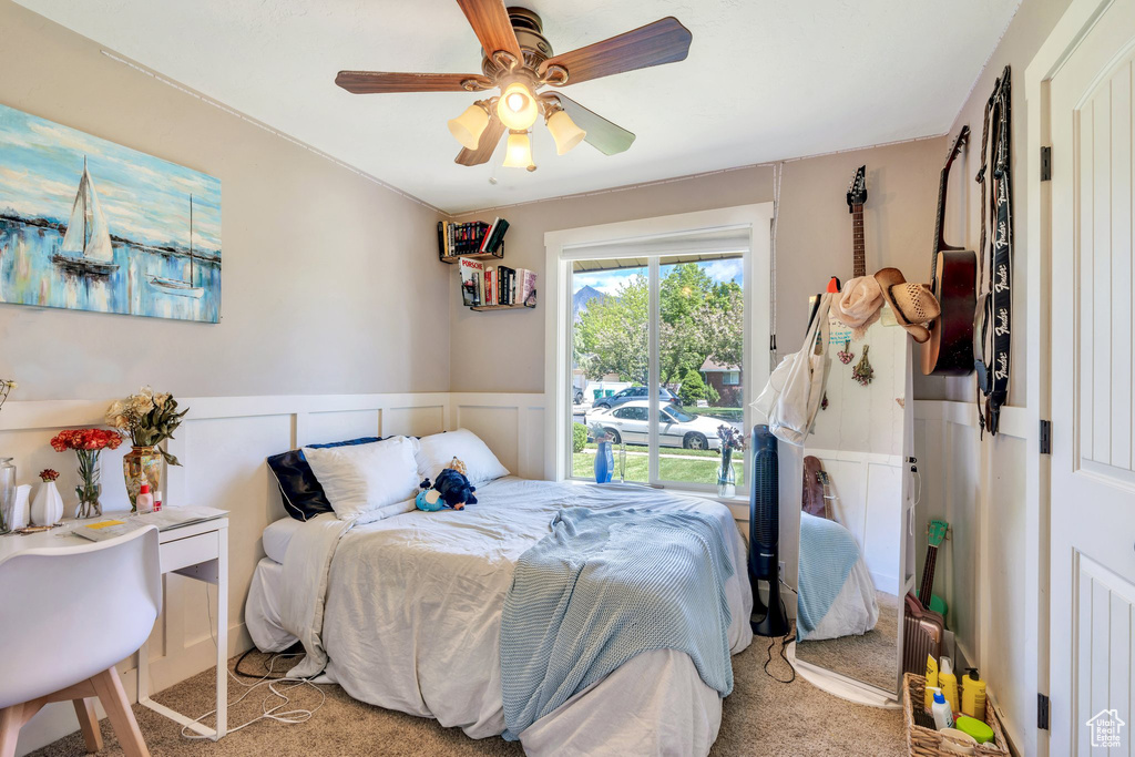 Carpeted bedroom with wainscoting and a ceiling fan